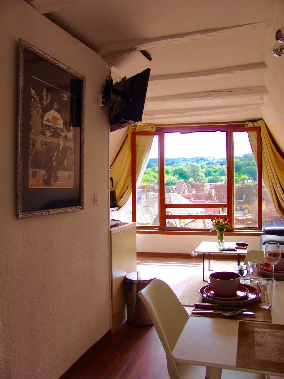 un salon avec une table et une grande fenêtre dans l'établissement Appartement la Belle Vue Panoramique, à Sarlat-la-Canéda