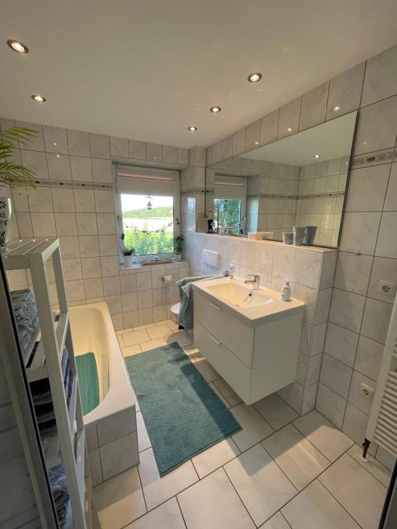 a bathroom with a sink and a tub and a mirror at Ferienwohnung Ahoi in Langwedel