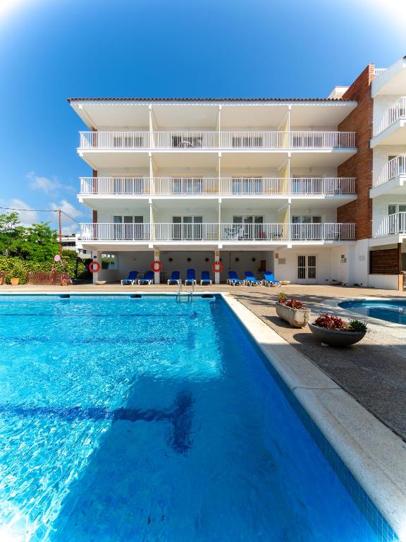 a swimming pool in front of a building at Apartamentos Sunway Amapola in Sitges