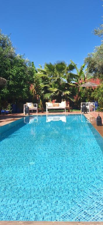 uma grande piscina azul com árvores ao fundo em Beldicolors em Marraquexe