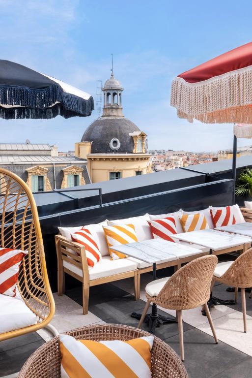 a patio with chairs and tables on a roof at Doubletree By Hilton Nice Centre Iconic in Nice