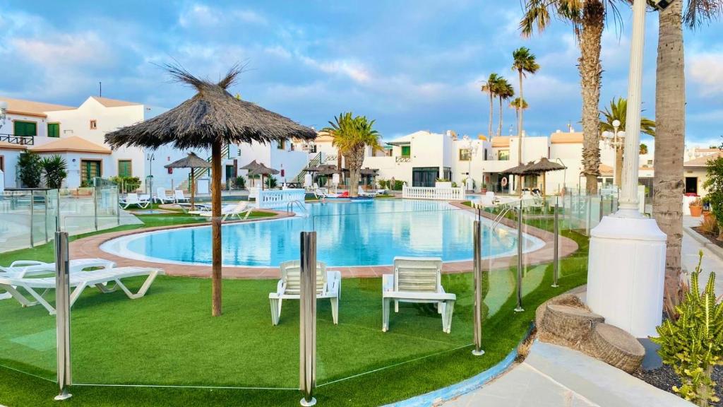 a pool at a resort with chairs and a umbrella at Happiness in Caleta De Fuste