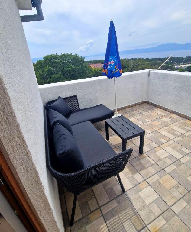 a couch and a table on a balcony with an umbrella at Apartman Seka in Kraljevica