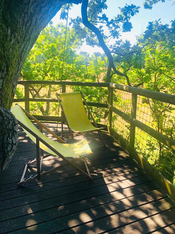 deux chaises assises sur un porche avec une balançoire dans l'établissement Les Noctam'bulles - Cabanes dans les arbres, à Saint-Pierre-Azif