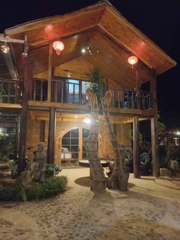 une maison avec une statue devant dans l'établissement K50 Waterfall Village - Homestay Măng Đen, à Kon Plong