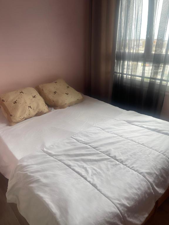 - un lit avec des draps et des oreillers blancs à côté d'une fenêtre dans l'établissement la maison, à Pantin