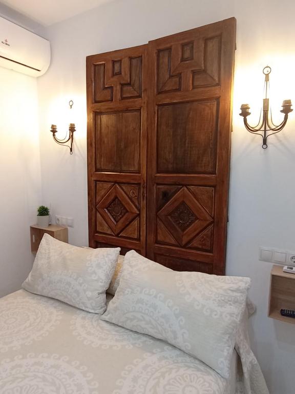 a bed with a wooden headboard and two white pillows at El DETALLE Apartamento y Estudio in Zahara de la Sierra