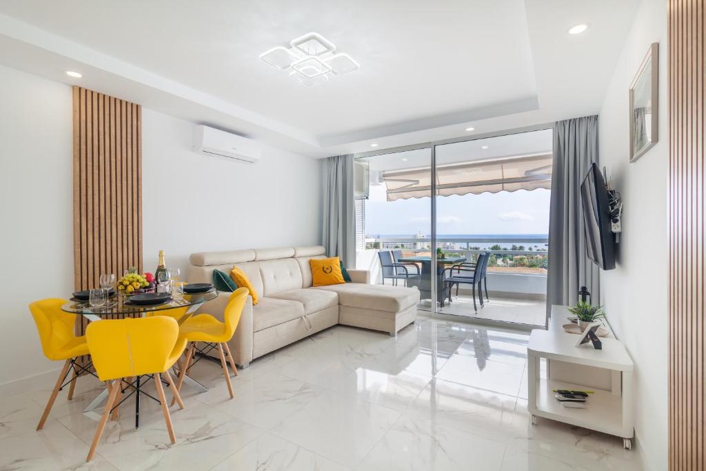 a living room with a couch and a table and chairs at Ponderosa 611, Las Americas, one bedroom apartment with large terrace and ocean view, next to Siam Park in Playa Fañabe
