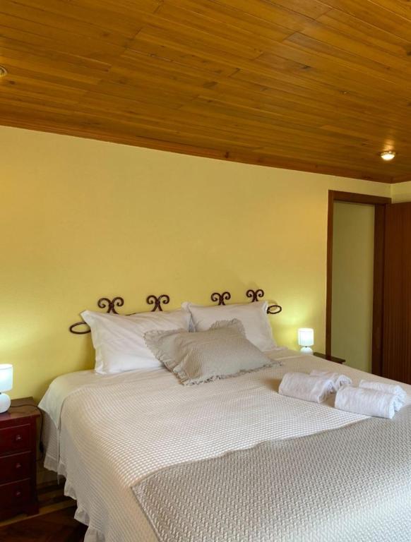 a bedroom with a large white bed with two lamps at Casa do Portão Azul - Dourada in Atouguia da Baleia