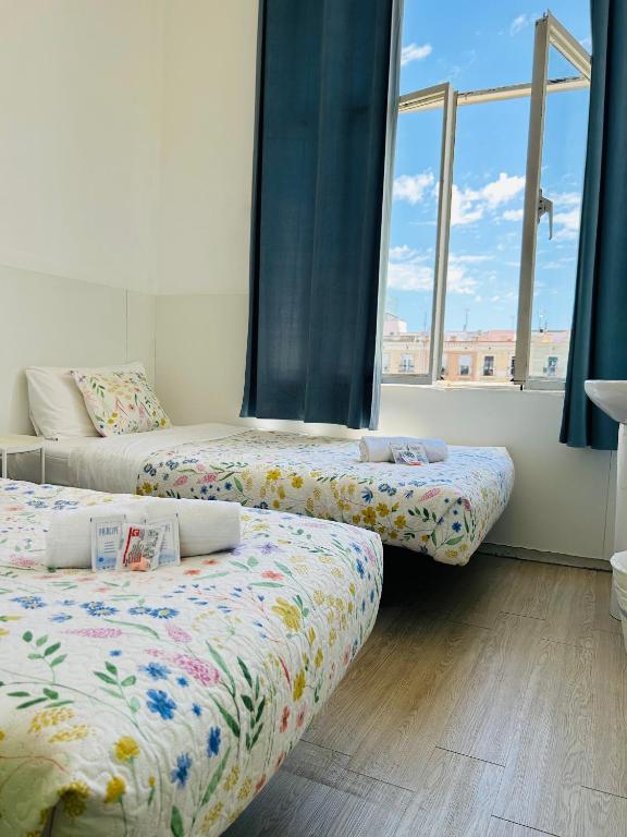 two beds in a room with two windows at Central and Basic Universitat for YOUNG HOSTEL in Barcelona