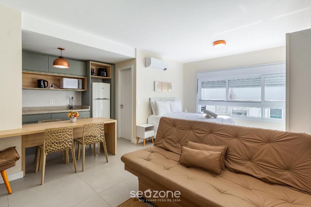 a living room with a couch and a kitchen and a bedroom at Studio encantador e bem localizado PoA-RS VENB504 in Partenon
