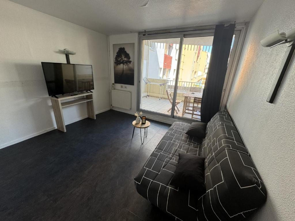 un salon avec un canapé et une télévision à écran plat dans l'établissement Appartement - Cap d'Agde, au Cap d'Agde