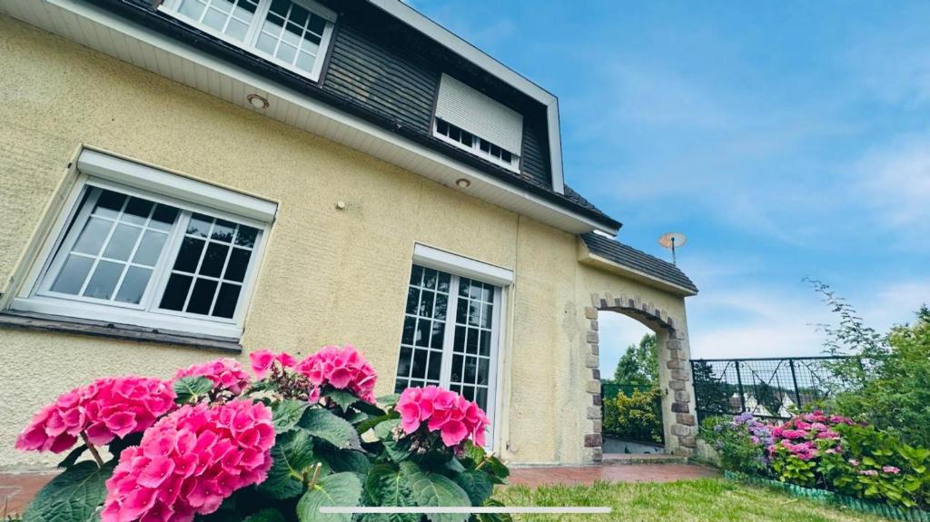 une maison avec des fleurs roses devant elle dans l'établissement Maison de Tara à la mer, à Étaples