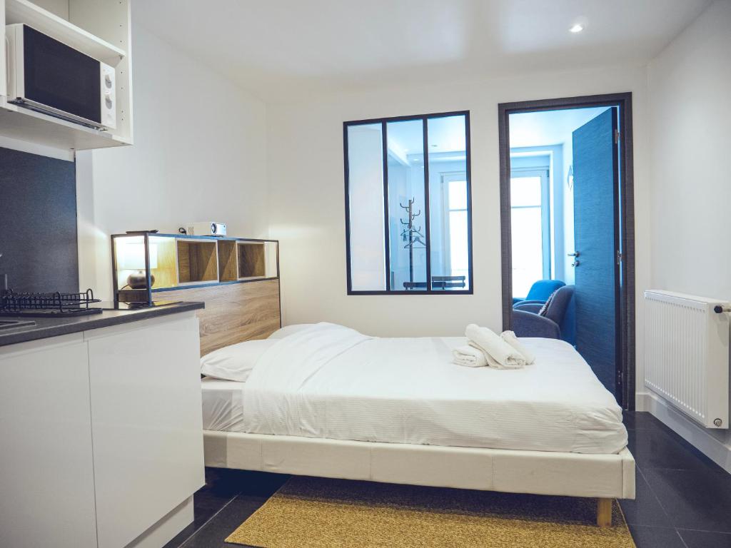 une chambre avec un lit blanc et une fenêtre dans l'établissement Studio contemporain hypercentre, à Nancy