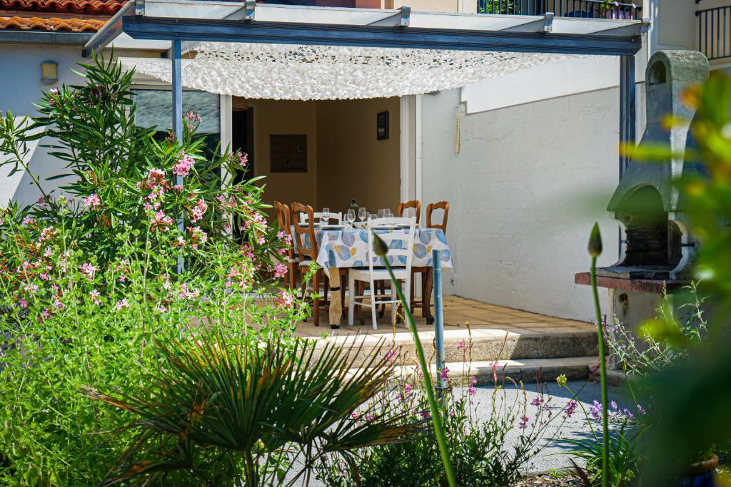 - une table à manger et des chaises sur une terrasse fleurie dans l'établissement Maison de vacances quartier Arago Les Sables - 6 personnes, à Les Sables-dʼOlonne