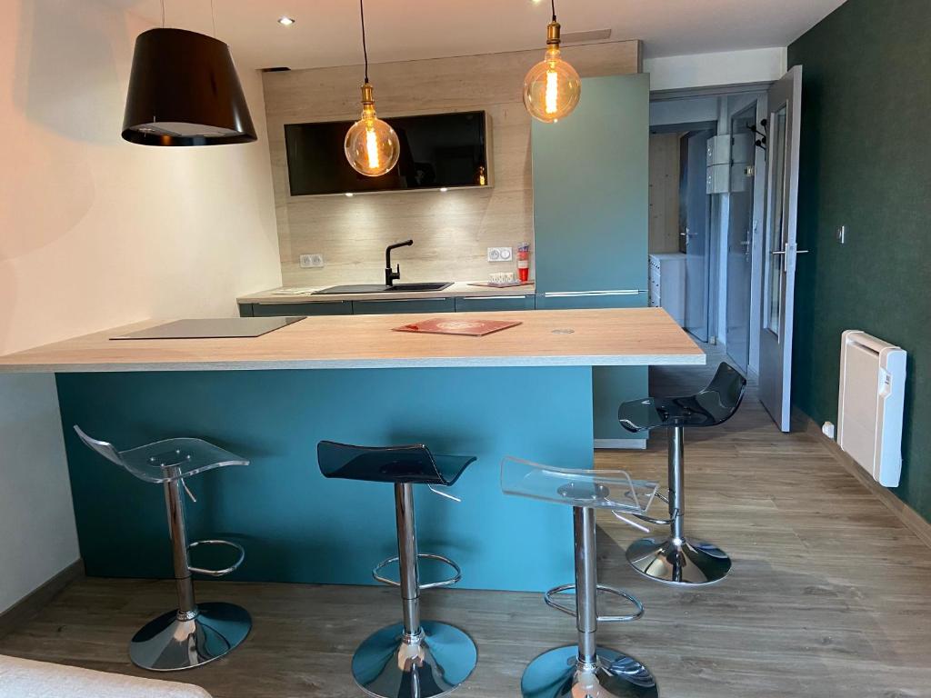 une cuisine avec quatre tabourets de bar sous un comptoir dans l'établissement Le Claret, à Autrans