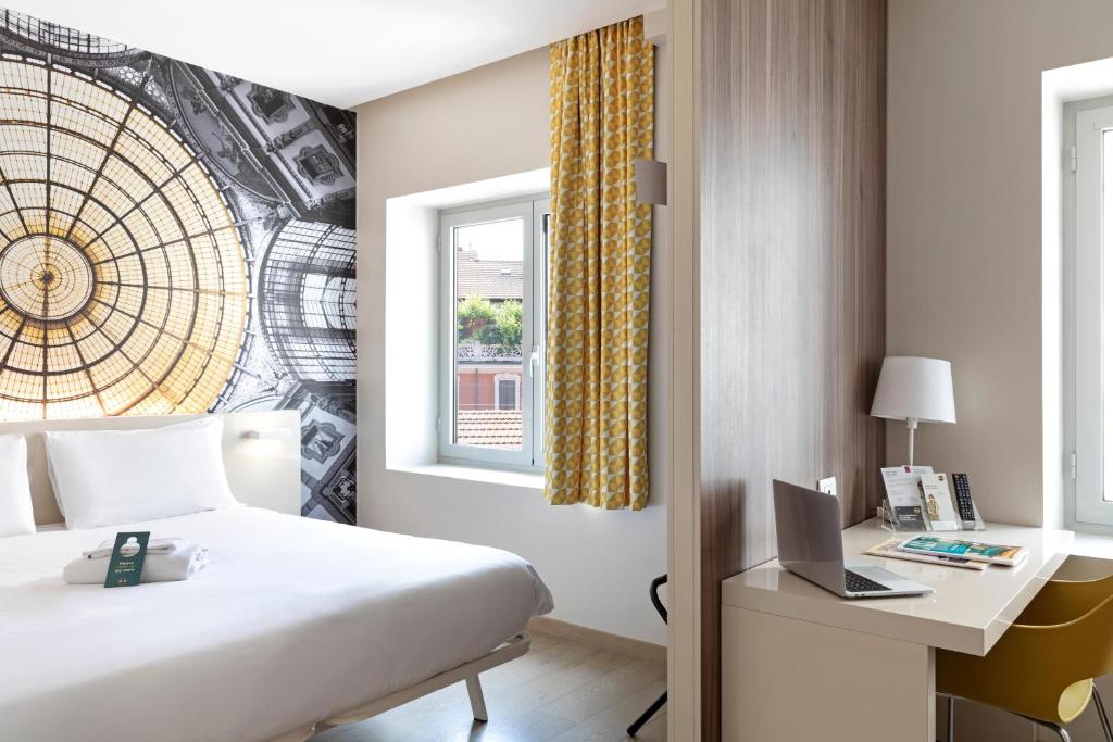 a hotel room with a bed and a desk and a window at B&B Hotel Milano Central Station in Milan