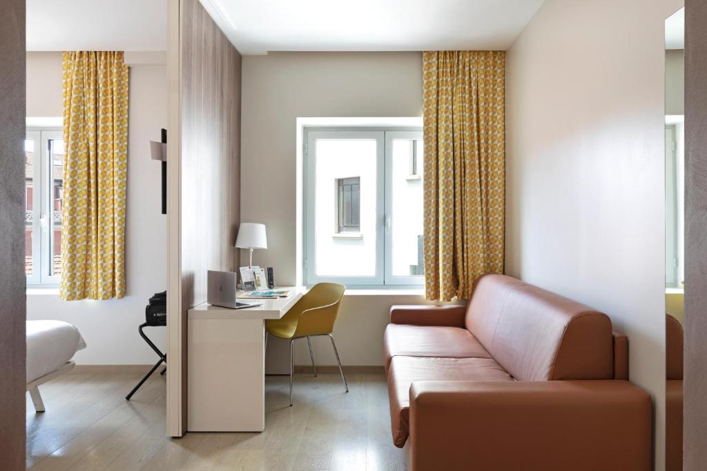 a living room with a couch and a desk at B&B Hotel Milano Central Station in Milan
