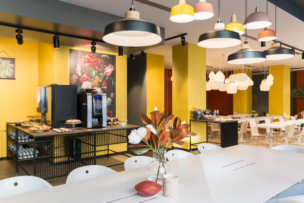 a restaurant with yellow walls and white tables and chairs at B&B Hotel Milano Central Station in Milan
