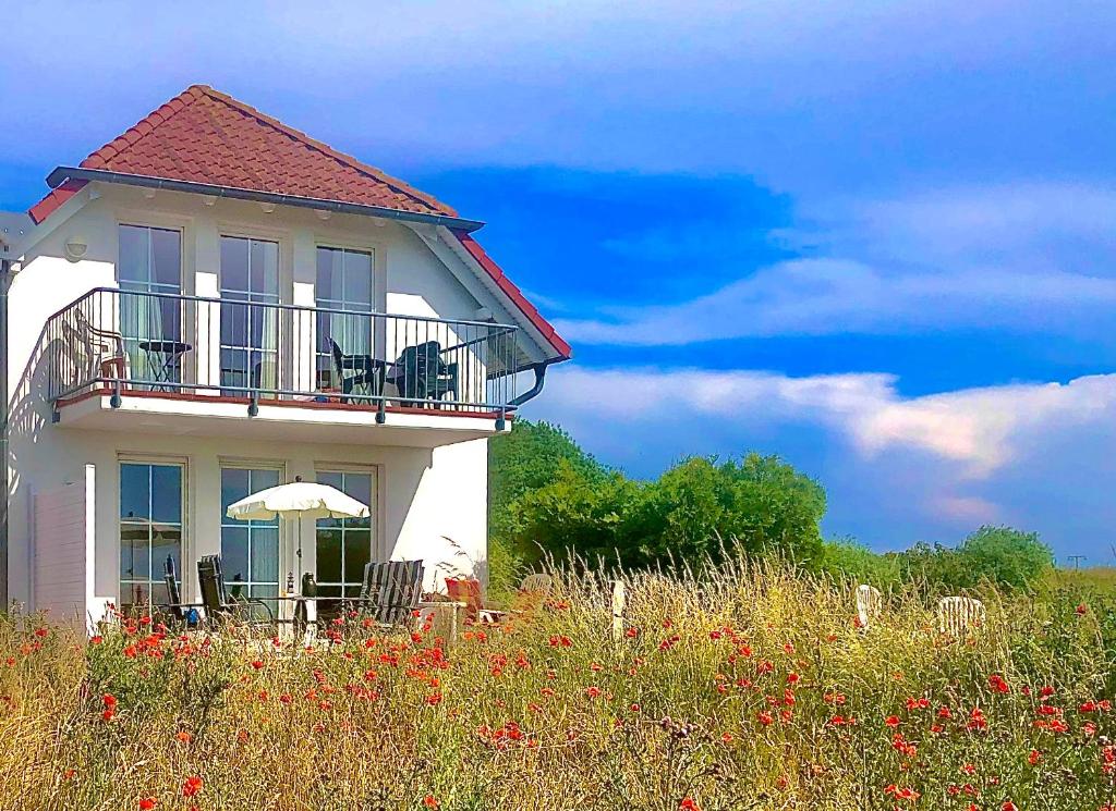 a white house with a balcony and an umbrella at Schöne Wohnung mit Boddenblick in Sagard