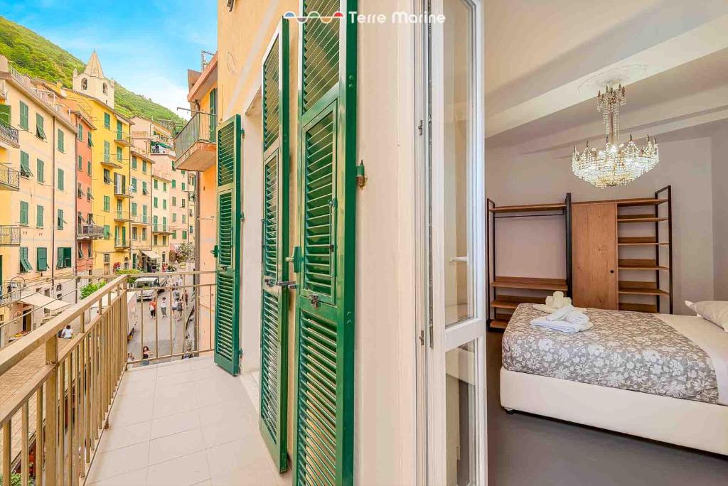 a bedroom with a bed and a balcony with green shutters at Luci Danzanti, Terre Marine in Riomaggiore