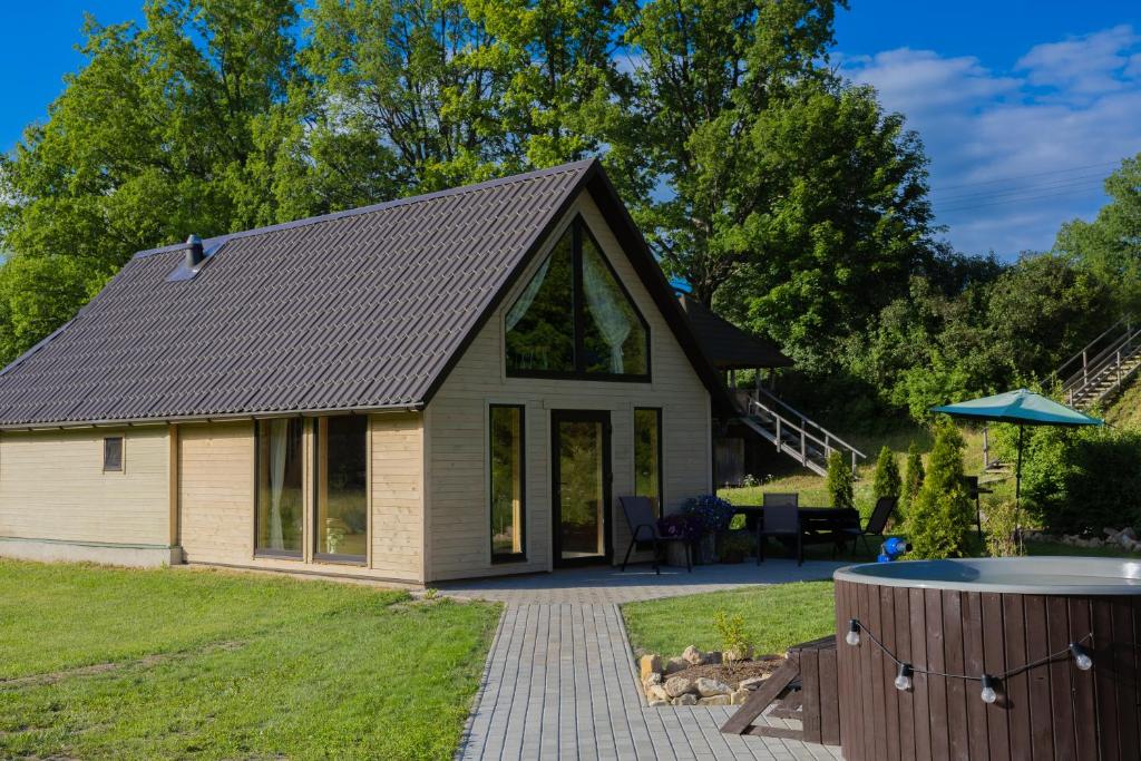 a cottage with a patio and a hot tub at Kalna Smīžu pirtiņa in Melturi