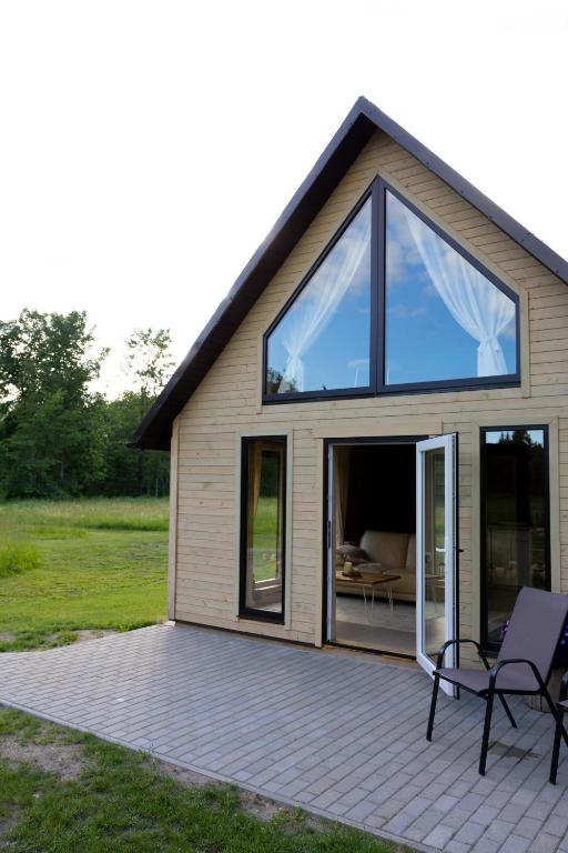 a house with glass doors and a patio at Kalna Smīžu pirtiņa in Melturi