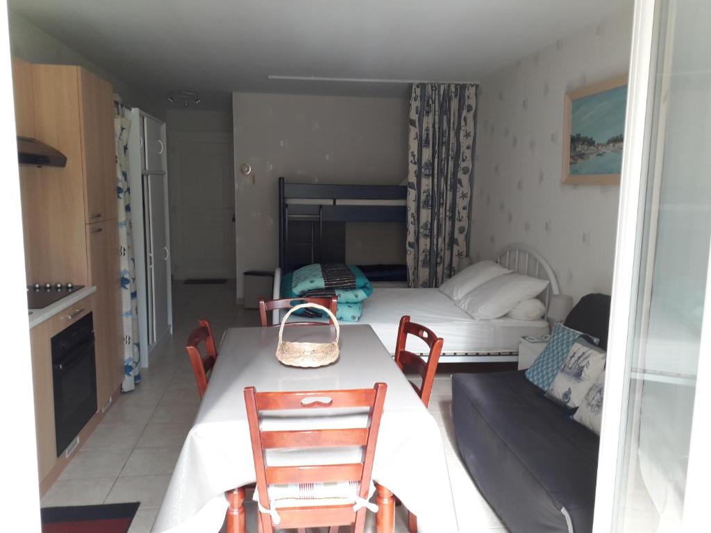 Cette petite chambre comprend deux lits, une table et des chaises. dans l'établissement Le coin paisible, à Gujan-Mestras