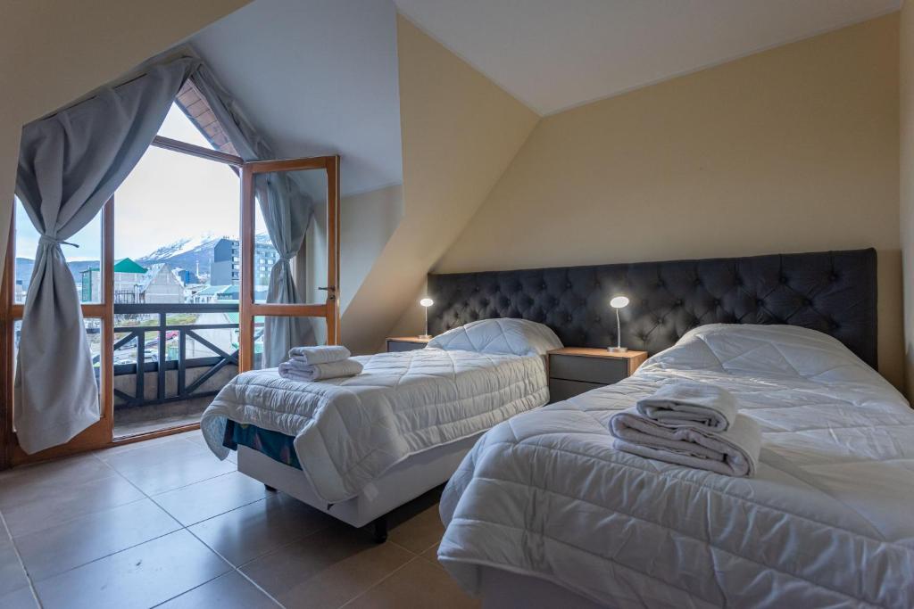 two beds in a hotel room with a balcony at Gente del Sur - Odino in Ushuaia