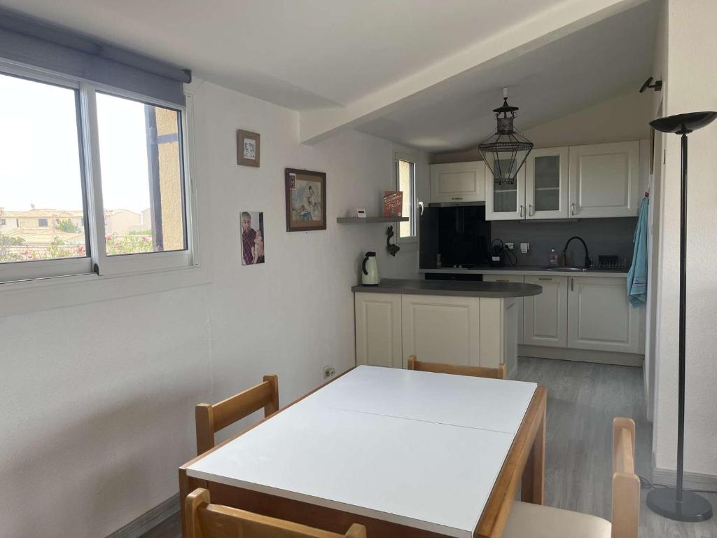 une cuisine avec une table blanche et une table et des chaises dans l'établissement Appart 3 pièces 2 couchages PORT LEUCATE NATURISME PL010-071, à Leucate