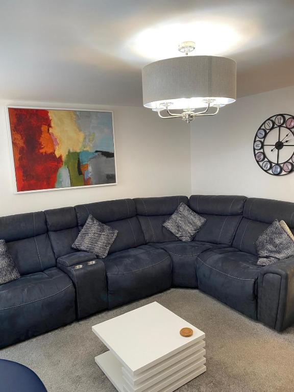 a living room with a blue couch and a clock at Mossie Apartment in Ayr