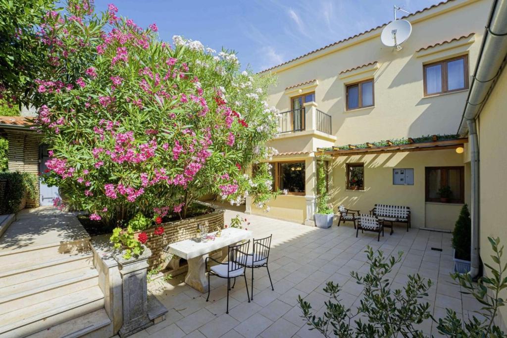 a patio with a table and a tree with pink flowers at Villa Ene in Pula - Haus für 6 Personen in Pula