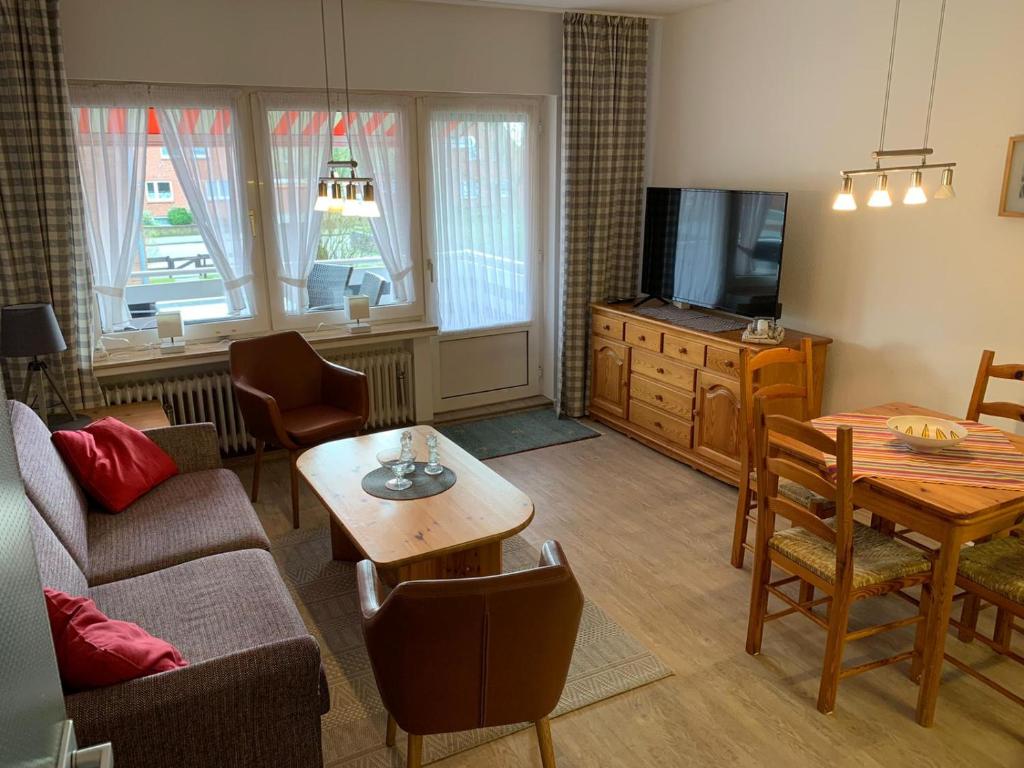 un soggiorno con un divano, un tavolo e una TV di Sonnige Ferienwohnung a Borkum