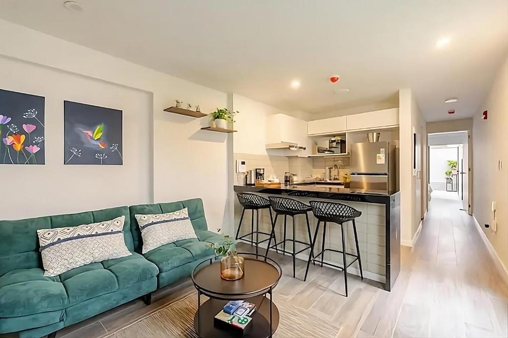 Una sala de estar con un sofá verde y una cocina. en Premiere apartment in the heart of Barranco, a block away from Central restaurant, en Lima