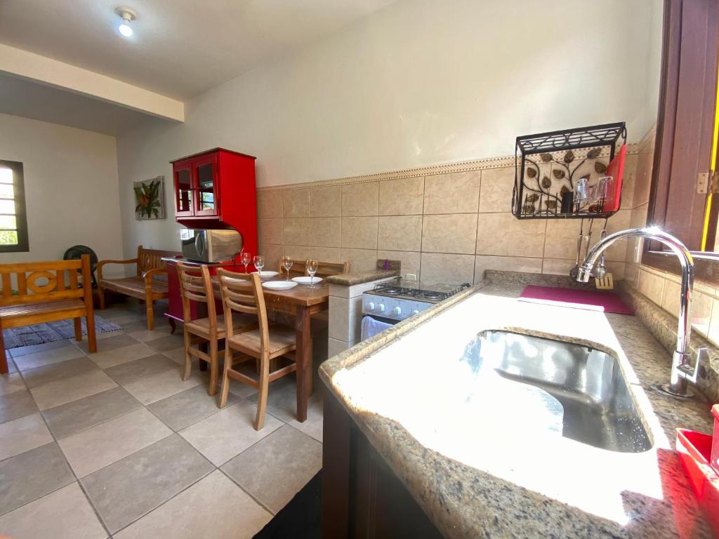 a kitchen with a sink and a dining room with a table at Casa 300 m Praia Jabaquara in Paraty