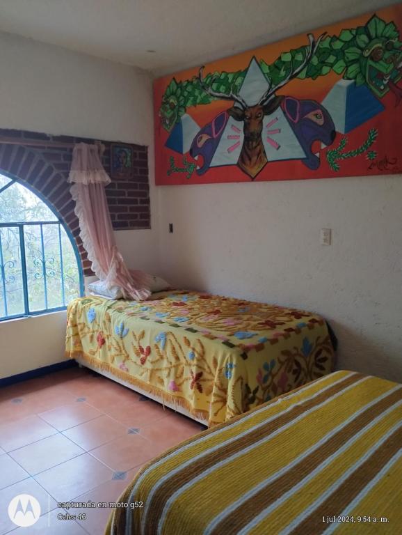 a bedroom with two beds and a painting on the wall at Casa Ecológica Pablo in Curva La Pera