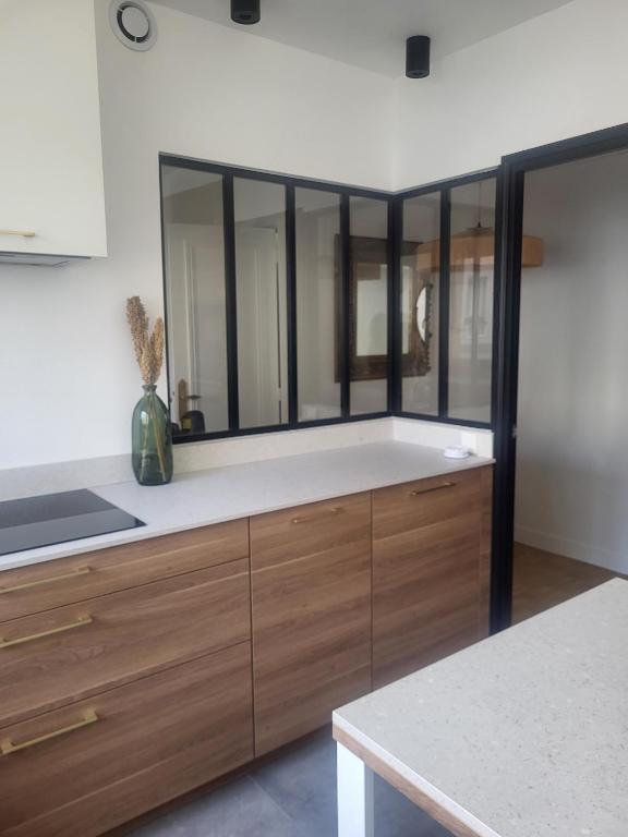 - une cuisine avec des placards en bois et un grand miroir dans l'établissement Appart Nicette, à Courbevoie