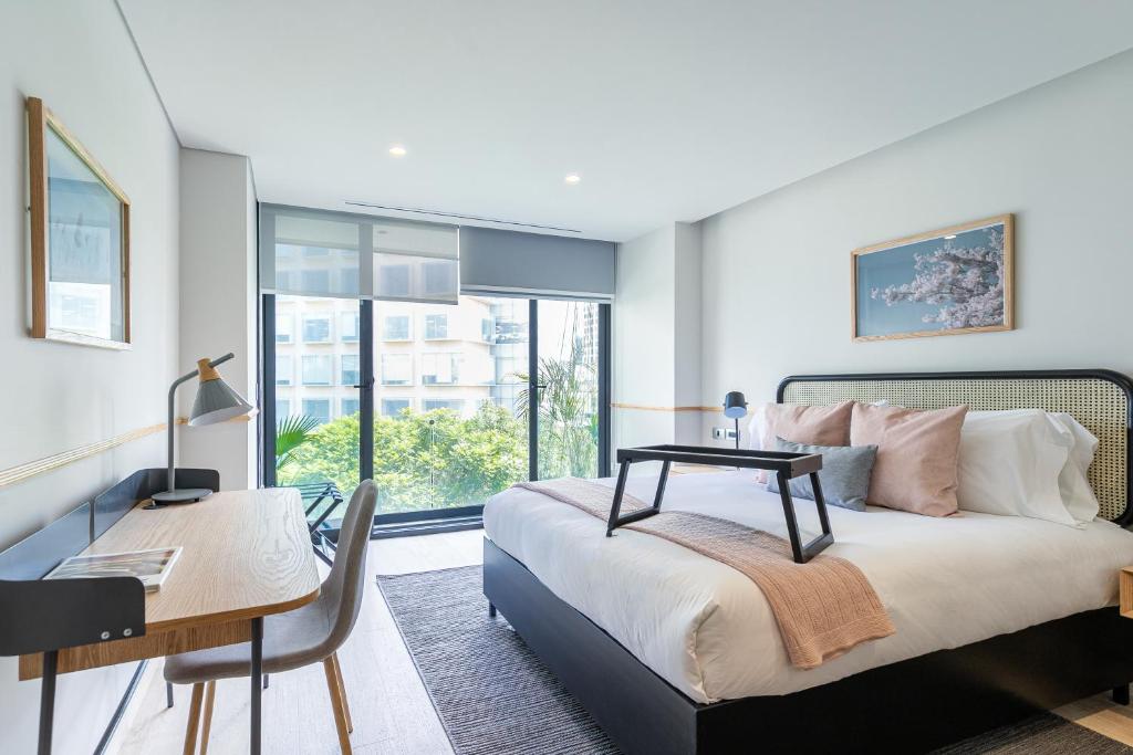 A bedroom with a double bed, window, and built-in work desk.