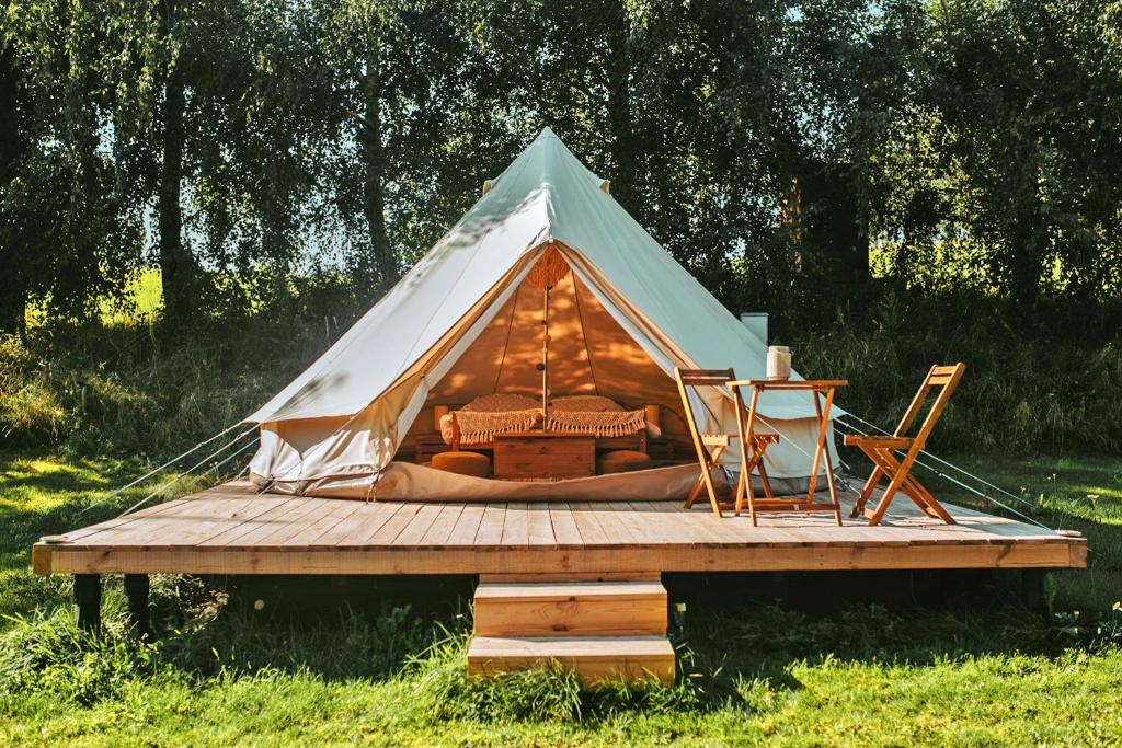 MiłkiMiła Łąka Glamping的木制甲板上的帐篷,配有一张床