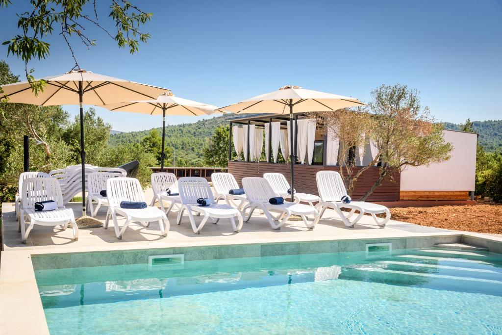 a group of chairs and umbrellas next to a pool at Luxury and Cosy Little House Ivinj 1 in Tisno