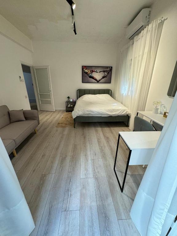 a bedroom with a bed and a couch and a table at 3 rooms apartment on the beach in Tel Aviv
