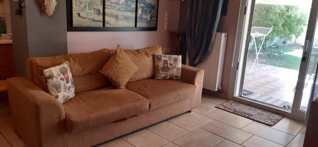 a brown couch in a living room with a sliding glass door at Galini Garden House in Kavala