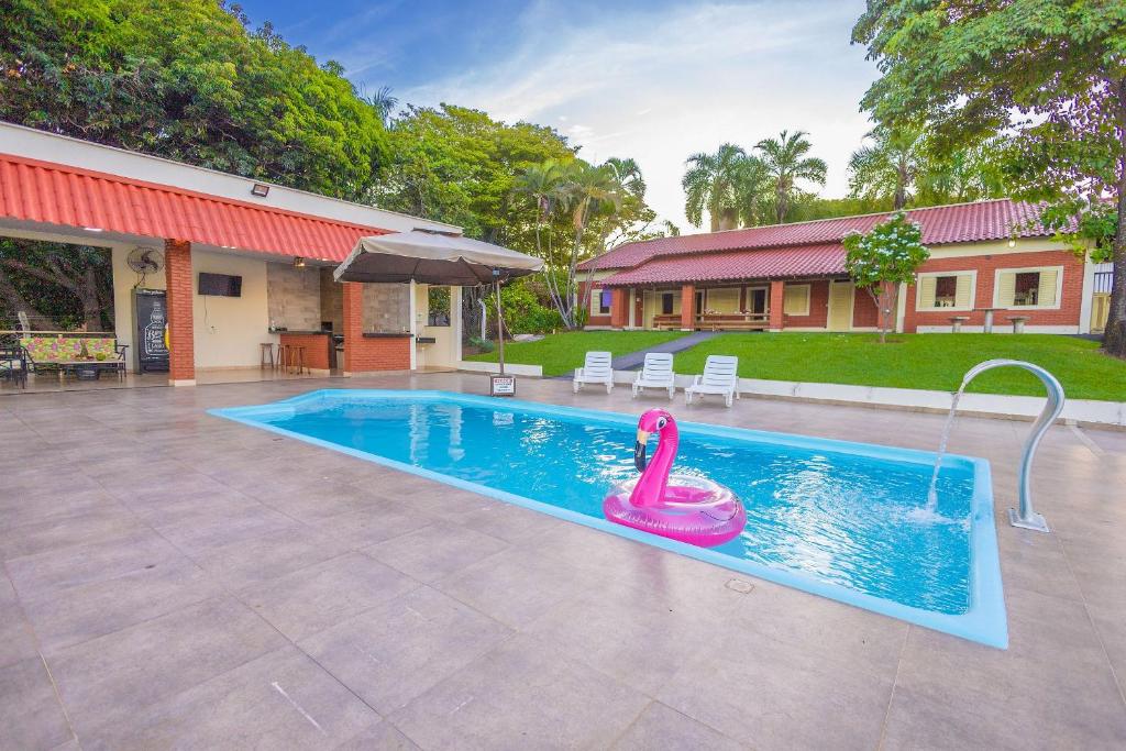 une piscine avec un gonflable rose en face d'une maison dans l'établissement Rancho Colonial 6 suítes acesso ao Lago das Brisas, à Corumbazul