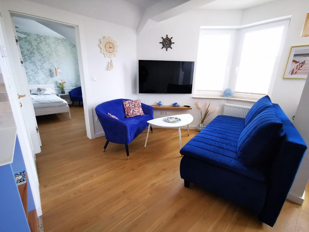 a living room with a blue couch and a table at Aravell E23 Darłówko Wschodnie in Darlowko