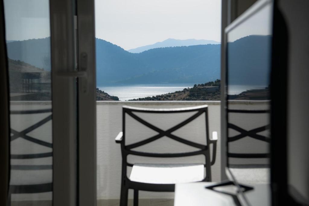 a chair sitting on a balcony looking out at the water at Villa Melodia Xhek in Ksamil