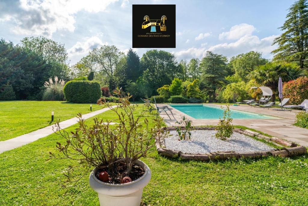a garden with a pool and a plant in a pot at Appartement Élégant, Climatisation et Piscine in Ormoy-la-Rivière