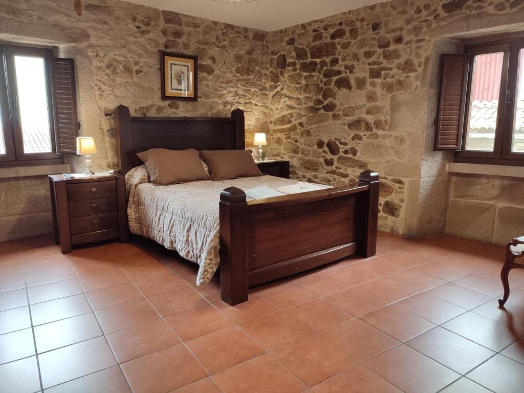 a bedroom with a bed and a stone wall at Casa Floriña in Outes