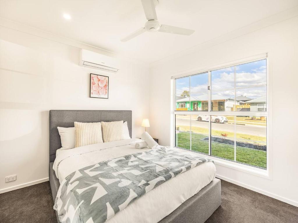 a bedroom with a bed and a large window at Modern Family Retreat in Premier GreenbankLocation in Springfield Lakes