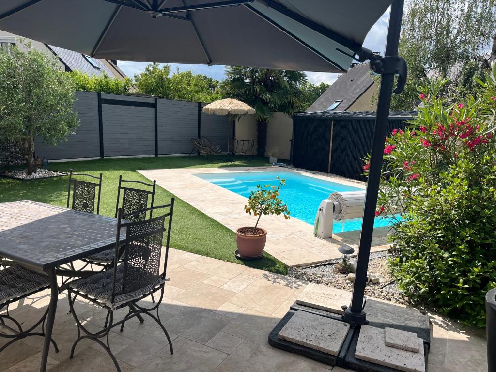a patio with a table and chairs and an umbrella at Élégante maison circuit des 24h00 du mans in Le Mans