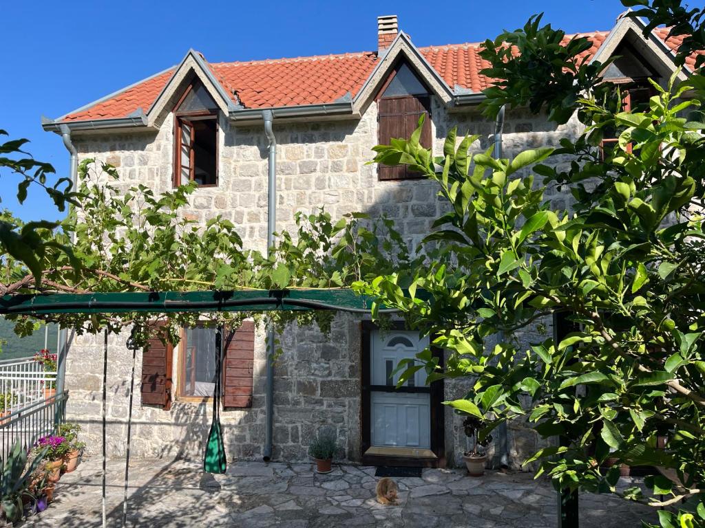 a stone house with a tree in front of it at Artist's House on the Mountain in Zelenika
